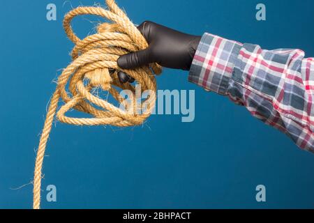 Corda gialla nella mano esperta di un adulto con protezione. Corda spessa per legare oggetti. Foto Stock