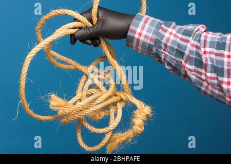 Corda gialla nella mano esperta di un adulto con protezione. Corda spessa per legare oggetti. Foto Stock