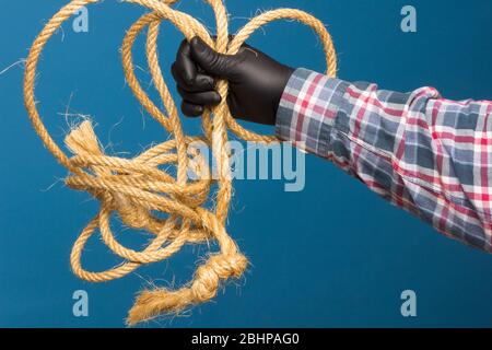 Corda gialla nella mano esperta di un adulto con protezione. Corda spessa per legare oggetti. Foto Stock