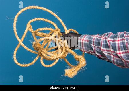 Corda gialla nella mano esperta di un adulto con protezione. Corda spessa per legare oggetti. Foto Stock