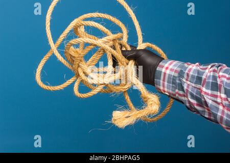 Corda gialla nella mano esperta di un adulto con protezione. Corda spessa per legare oggetti. Foto Stock