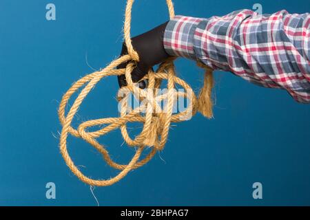 Corda gialla nella mano esperta di un adulto con protezione. Corda spessa per legare oggetti. Foto Stock