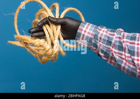 Corda gialla nella mano esperta di un adulto con protezione. Corda spessa per legare oggetti. Foto Stock