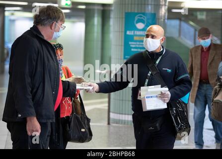 27 aprile 2020, Hessen, Francoforte sul meno: I dipendenti delle compagnie di trasporto si trovano alla stazione principale all'uscita della metropolitana e distribuiscono maschere facciali ai passeggeri. Dal 27.04.2020, le maschere sono obbligatorie anche per gli autobus e i treni in Assia. Foto: Boris Roessler/dpa Foto Stock