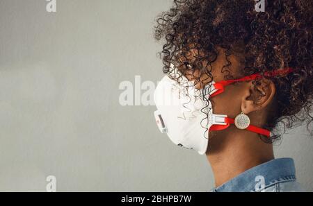 Profilo di una donna nera con maschera FFP3 con valvola espiratoria. Coronavirus. Protezione. Spazio di copia. Foto Stock