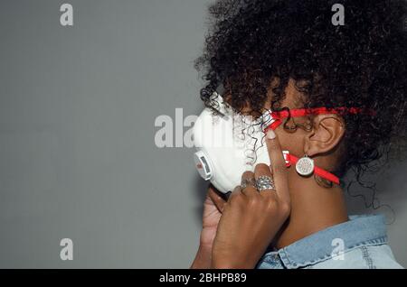 Profilo di una donna nera con maschera FFP3 con valvola espiratoria. Coronavirus. Protezione. Spazio di copia. Foto Stock