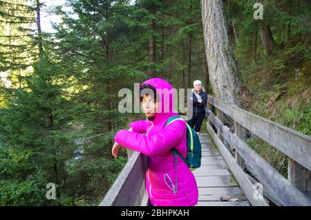 giovane ragazza in montagna seguita dalla rigorosa guida di montagna per i sentieri nei boschi Foto Stock