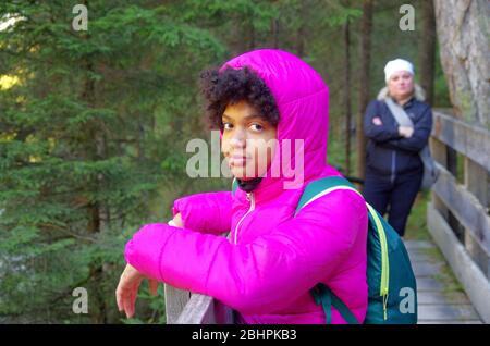 giovane ragazza in montagna seguita dalla rigorosa guida di montagna per i sentieri nei boschi Foto Stock