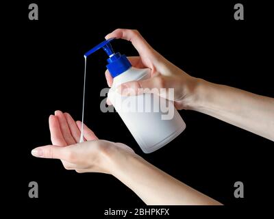 Donna che spinge le mani dispenser di sapone con goccia di sapone. Isolato su nero, tracciato di ritaglio incluso Foto Stock