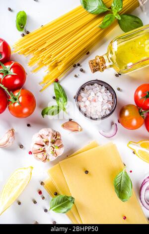 Ingredienti per cucinare gli Spaghetti Pasta. Spaghetti crudi con ingredienti vari - cipolla, pomodori, aglio, basilico, prezzemolo, formaggio, Foto Stock