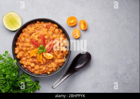 Medames o Fava Beans in ciotola nera sullo sfondo grigio. Foul Mudammas è un egiziano, libanese, siriano, eritreano, israeliano cucina piatti di colazione Foto Stock