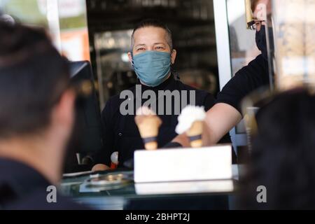 Hannover, Germania. 27 aprile 2020. Il fornitore di gelati Morris indossa una mentoniera sul lavoro. Da lunedì, le maschere sono obbligatorie in bassa Sassonia per i trasporti pubblici e i negozi. Credit: OLE Spata/dpa/Alamy Live News Foto Stock