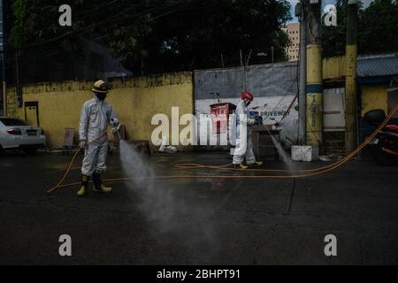 Luzon, Filippine. 27 aprile 2020. I volontari del fuoco spruzzano disinfettante su una strada a Mandaluyong City il lunedì 27 aprile 2020. La città continua la sua disinfezione regolare di strade e vicoli per frenare la diffusione del COVID-19. L'Ufficio di correzioni ha confermato 27 altri detenuti dell'Istituto Correctional per le Donne nella città testato positivo per il coronavirus. (Foto di Larry Monserate Piojo/Sipa USA) Credit: Sipa USA/Alamy Live News Foto Stock