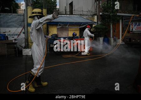 Luzon, Filippine. 27 aprile 2020. I volontari del fuoco spruzzano disinfettante su una strada a Mandaluyong City il lunedì 27 aprile 2020. La città continua la sua disinfezione regolare di strade e vicoli per frenare la diffusione del COVID-19. L'Ufficio di correzioni ha confermato 27 altri detenuti dell'Istituto Correctional per le Donne nella città testato positivo per il coronavirus. (Foto di Larry Monserate Piojo/Sipa USA) Credit: Sipa USA/Alamy Live News Foto Stock