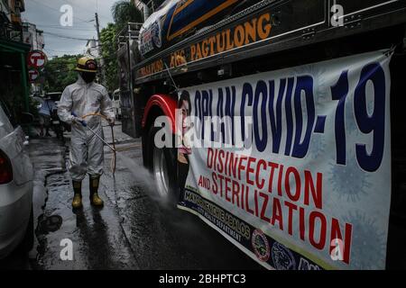 Luzon, Filippine. 27 aprile 2020. I volontari del fuoco spruzzano disinfettante su una strada a Mandaluyong City il lunedì 27 aprile 2020. La città continua la sua disinfezione regolare di strade e vicoli per frenare la diffusione del COVID-19. L'Ufficio di correzioni ha confermato 27 altri detenuti dell'Istituto Correctional per le Donne nella città testato positivo per il coronavirus. (Foto di Larry Monserate Piojo/Sipa USA) Credit: Sipa USA/Alamy Live News Foto Stock