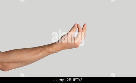 Ragazzo giovane che tiene qualcosa su sfondo grigio chiaro, primo piano. Spazio di copia. Panorama Foto Stock