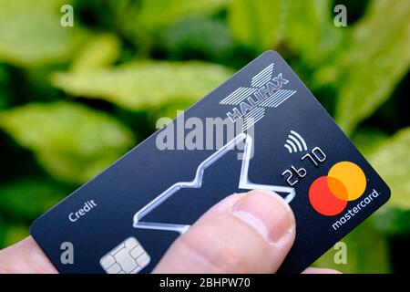 Stone / Regno Unito - Aprile 26 2020: Carta di credito Halifax Mastercard tenere in mano su sfondo verde. Foto Stock