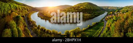Panoramica foto di paesaggio aereo del fiume Neckar, Germania, ad un bellissimo tramonto, con cielo limpido e la vegetazione è illuminata coloratissimo, una strada seguire Foto Stock