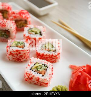 Sushi con chopsticks, zenzero, salsa di soia e wasabi. Cibo giapponese. Set di sushi roll con verdure, pesce e caviale. Menu del ristorante Giapponese Foto Stock