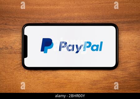 Uno smartphone con il logo PayPal è posizionato su un tavolo di legno (solo per uso editoriale). Foto Stock