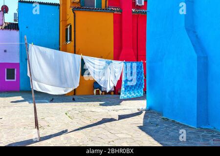 Lavanderia appesa sulla linea tra case colorate di Burano, Italia. Foto Stock