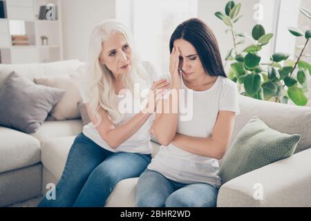 Caro che cosa è accaduto. Frustrata vecchia donna teo persone mamma sua figlia irritata grido sentire mal di testa emicrania touch fronte aiuto fiducia nella comodità camera accogliente Foto Stock