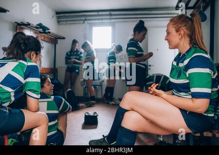 Donne che indossano magliette da rugby verdi, blu e bianche in un spogliatoio. Foto Stock