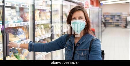 Donna che indossa la maschera medica monouso shopping in supermercato Foto Stock