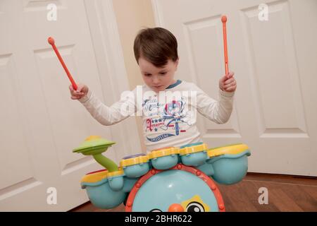 Ragazzo di due anni che suona la batteria a casa Foto Stock