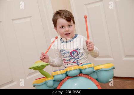 Ragazzo di due anni che suona la batteria a casa Foto Stock