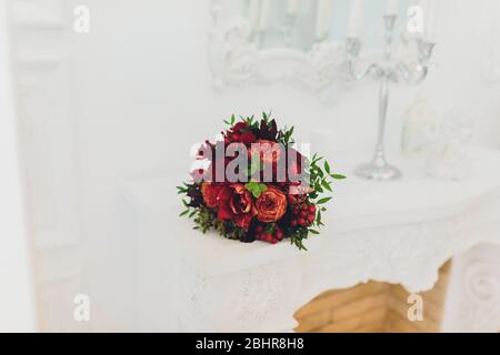 Bouquet nuziale di gigli si trova sul camino del Palazzo. Prossimo stand candela. Sullo sfondo di specchi antichi Foto Stock