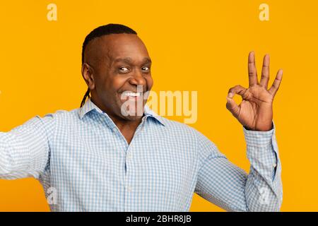 Felice uomo africano di mezza età che fa selfie e che mostra OK Foto Stock
