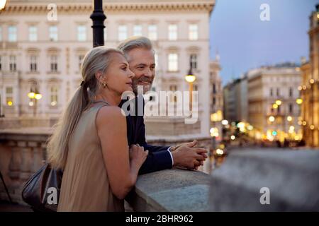 Una coppia si appoggia contro una balaustra che si affaccia su Vienna durante la sera. Foto Stock