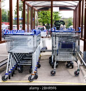 I carrelli Tesco Supermarket inutilizzati in attesa di acquirenti ascoltare i consigli di Government Lockdown durante il British Coronavirus o Covid-19 Pandemic Foto Stock