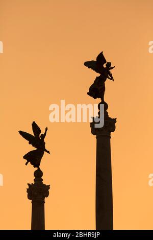 Roma, Italia. Angeli in cima alle colonne che fiancheggiano il Monumento a Vittorio Emanuele II Foto Stock