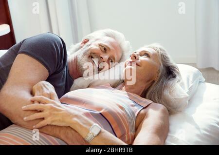 Una coppia che si stesa su un letto insieme e sorridente. Foto Stock