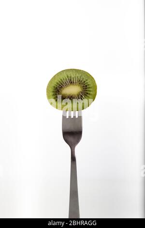 Una metà di un kiwi forati su una forcella su sfondo bianco Foto Stock