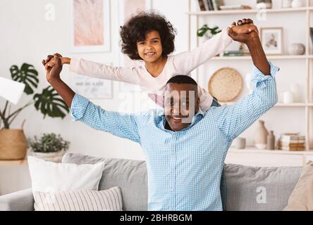 Giocate con il nonno. Uomo africano americano maturo che gioca gioco divertente con la nipote a casa Foto Stock