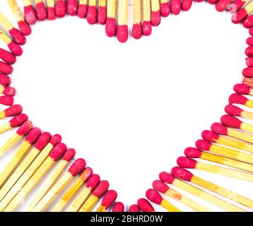 Un cuore fatto con bastoncini rossi di corrispondenza davanti ad uno sfondo bianco isolato Foto Stock