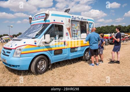 Il pulmino per gelato in una fiera locale fa la fila per acquistare il gelato in una calda giornata estiva Foto Stock