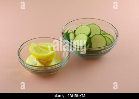 Fette di zucca cruda e spicchi di limone in ciotole di vetro su sfondo rosa Foto Stock