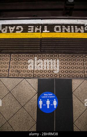 Londra, Regno Unito. 27 aprile 2020. Tieni i segnali di 2 m e fatti un'idea del gioco: I numeri dei passeggeri sono drammaticamente in basso sulla metropolitana, anche durante l'ora di punta, mentre la gente ascolta le indicazioni del governo. Coloro che viaggiano obbediscono ai segni che sono ovunque e molte indossano maschere. Il blocco continua per l'epidemia di Coronavirus (Covid 19) a Londra. Credit: Guy Bell/Alamy Live News Foto Stock