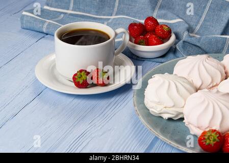Tazza di caffè americano e zephyr o marshmallow fatti in casa in un piatto blu su sfondo di legno blu chiaro. Foto Stock