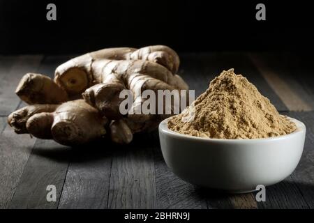 Radica lo zenzero in una ciotola su una tavola di legno. Foto Stock