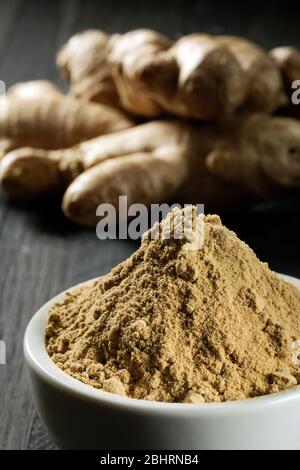 Radica lo zenzero in una ciotola su una tavola di legno. Foto Stock