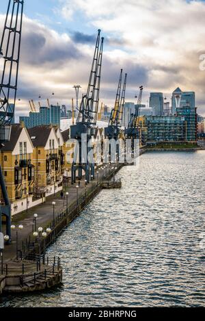 Londra, Inghilterra. Britannia Village e le sue gru viste dal Royal Victoria Dock Bridge con i grattacieli di Canary Wharf sullo sfondo. Foto Stock