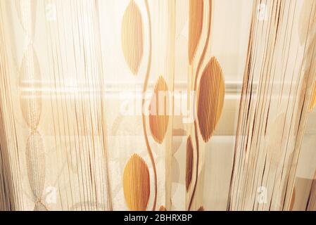 Finestra di un balcone con tende trasparenti e vista del sole mattutino e del mare Foto Stock