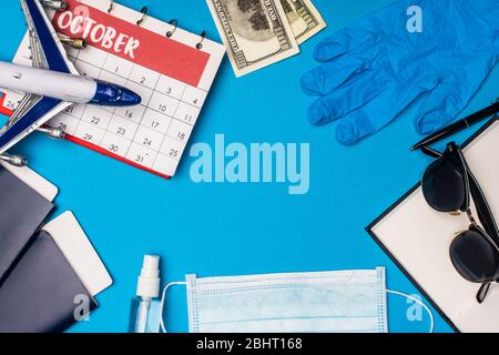 Vista dall'alto dell'aereo giocattolo, passaporti con biglietti aerei vicino al calendario e maschera medica su sfondo blu Foto Stock