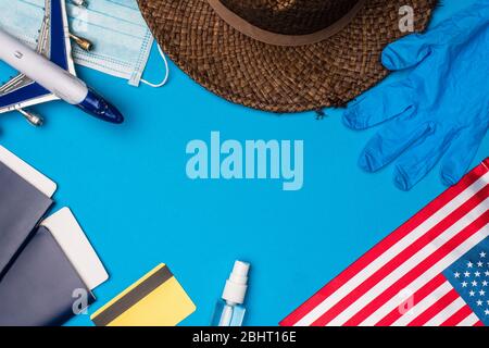 Vista dall'alto dei passaporti vicino all'aereo giocattolo vicino alla maschera medica e alla bandiera americana su sfondo blu Foto Stock