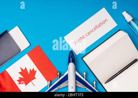 Vista dall'alto dell'aereo giocattolo, carta con scritta di cancellazione del volo e bandiera del canada su sfondo blu Foto Stock